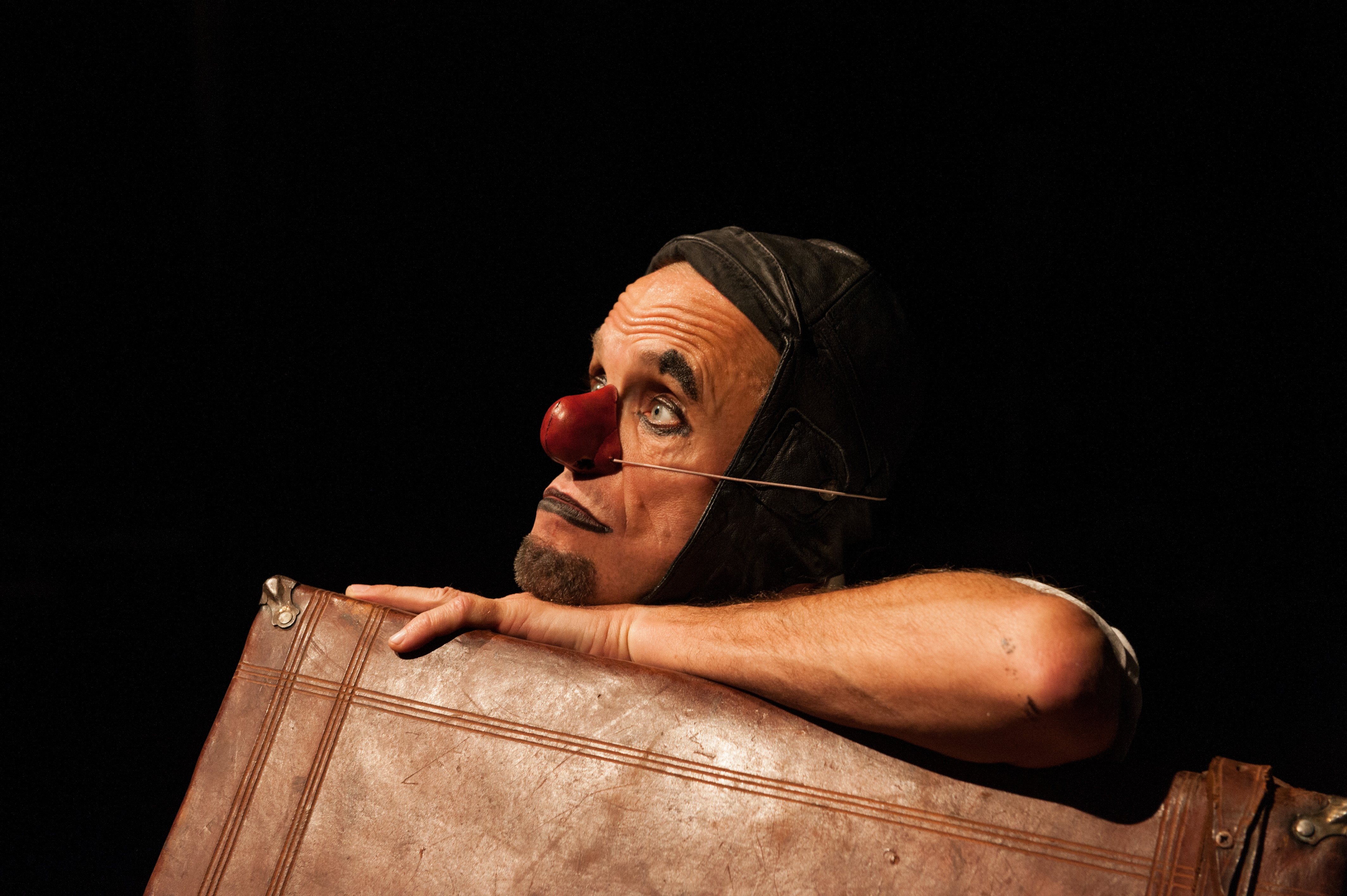 Una scena tratta da "Il viaggio di Giovannino", nella quale si vede il volto di un clown, appoggiato su una valigia